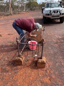 Craig Gunn cleaning the headstone of Ceceilia Gunn's grave at Bulong in 2023