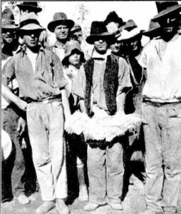 WITH THE RCCORD NUGGET: Mick Larkin, who with three others discovered the Larkinville field, holding the "Golden Eagle" nugget. On the right is Mr. J. J. Larcombe, on whose claim the nugget was found. On the left is M,.Larcombe, junior, finder of the nugget.
