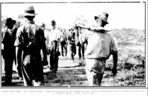 AFTER THE FIND: The "Golden Eagle" nugget being carried to the Larkinville store, where an attempt was made to weigh it by balancing iton a board, against a 70lb. bag of sugar.