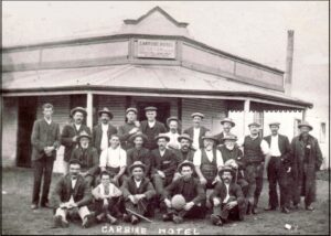 The Carbine Hotel - Robert is in the middle row with a pipe and his son James sitting in front of him with a pipe and a ball. The two young boys further along in the middle and front row are most likely to be Robert's sons Stanley in the middle row and Ray in front of him.
